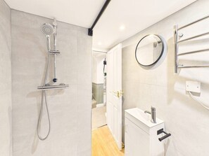 A modern bathroom with a shower, a sink, and a mirror.