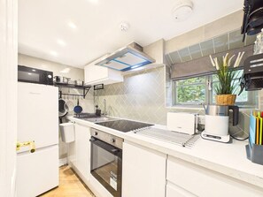 A modern kitchen with a built-in oven, a Bosch coffee maker, and a window with a view of greenery.
