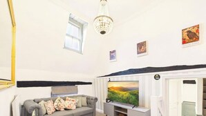 A living room with a flat-screen TV, a sofa, a chandelier, and artwork on the walls. - High Street | Boutique 2 Bedroom | Wi-Fi (Essex)