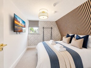 Una habitación de hotel con cama, televisión, ventana y puerta.