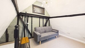 A room with a gray sofa, a black and white exposed beam ceiling, and a modern chandelier. - High Street | Boutique 2 Bedroom | Wi-Fi (Essex)