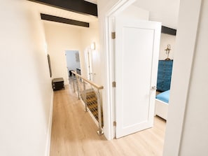 A hallway with a white door, a blue cabinet, and a staircase with a metal railing. - Beach Villa 2126: Rare 2-Story Gulf-Front Gem – Panoramic Views & Brand New Loft (Captiva)