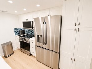 A modern kitchen with stainless steel appliances, white cabinetry, and a tiled backsplash. - Beach Villa 2126: Rare 2-Story Gulf-Front Gem – Panoramic Views & Brand New Loft (Captiva)