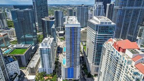 A high-rise building with a prominent blue stripe, surrounded by other tall buildings, indicating a dense urban area. - Chic City Condo With Pool & Gym (Miami)