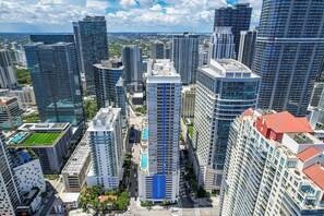 A high-rise building with a prominent blue stripe, surrounded by other tall buildings, indicating a dense urban area. - Chic City Condo With Pool & Gym (Miami)