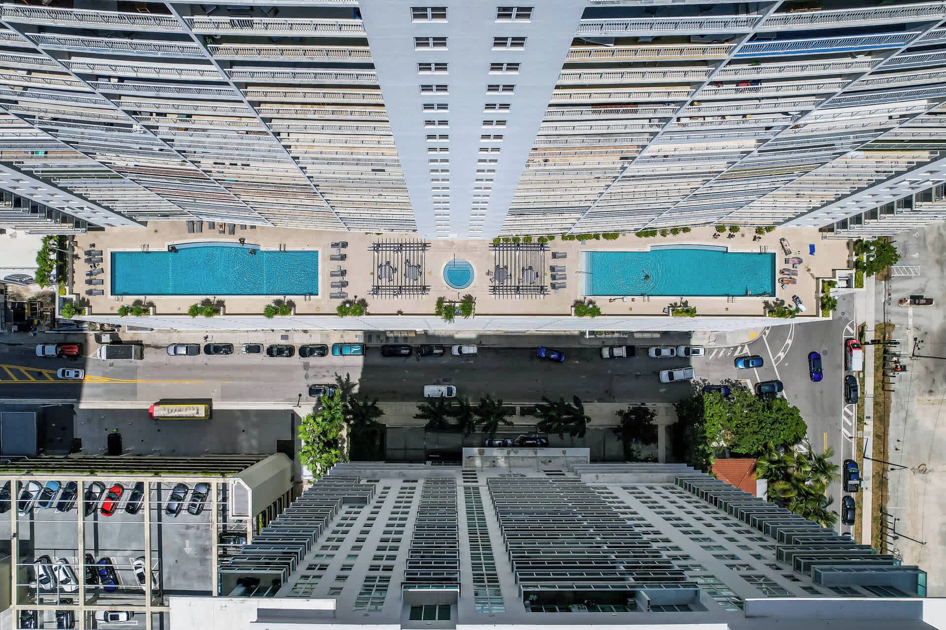 Un immeuble de grande hauteur doté de nombreux balcons, de deux piscines et d’un espace de stationnement.
