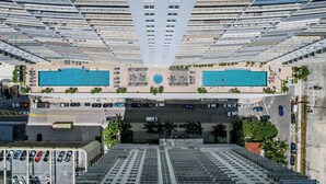 A high-rise building with multiple balconies, two swimming pools, and a parking area. - Chic City Condo With Pool & Gym (Miami)