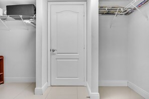 A white door with a simple design, a metal shelf above it, and a tiled floor. - Chic City Condo With Pool & Gym (Miami)