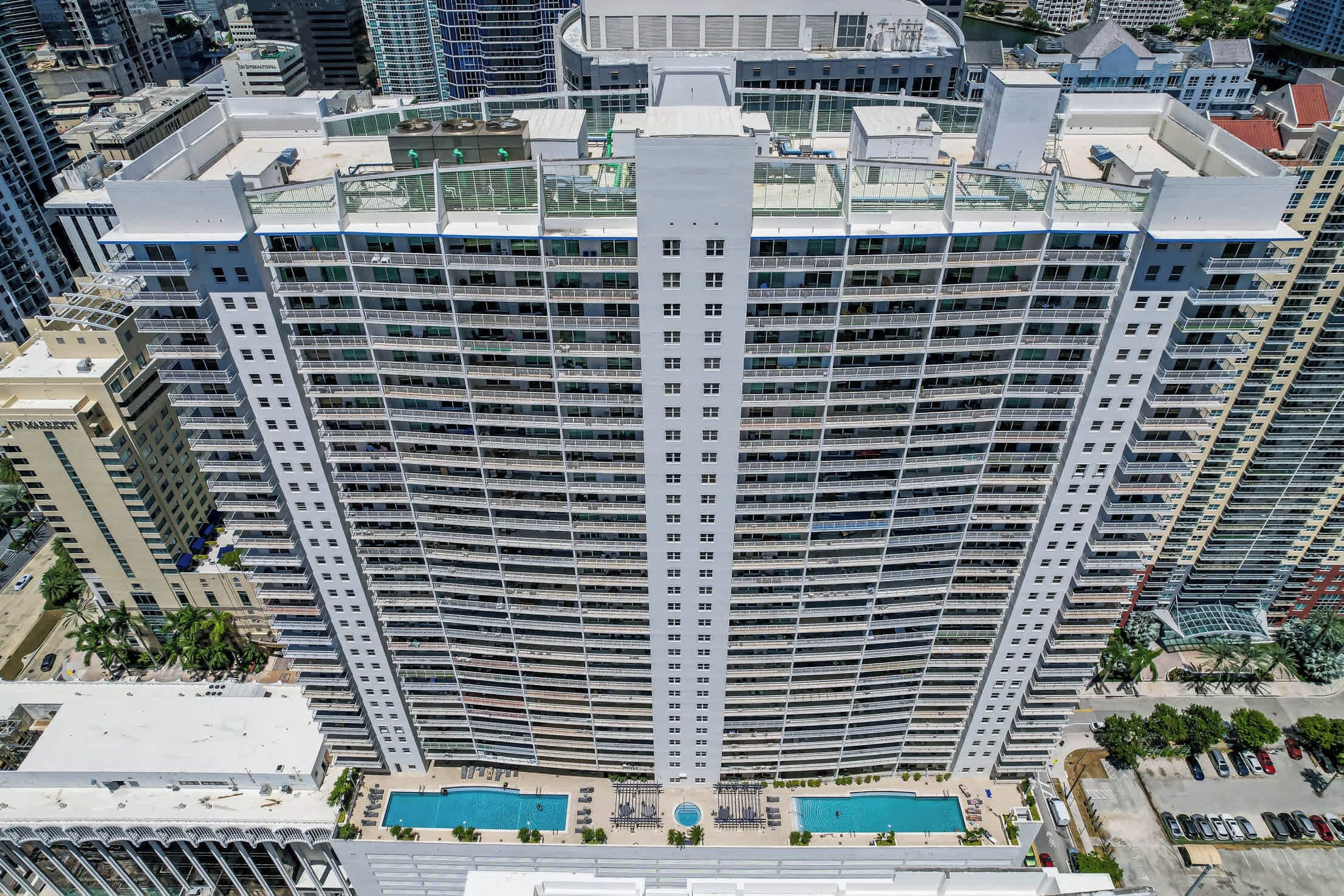 Un hôtel de grande hauteur doté de nombreux balcons, d’une piscine et d’un parking.