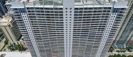 Un hôtel de grande hauteur doté de nombreux balcons, d’une piscine et d’un parking.