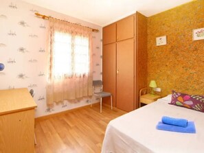 Ein Schlafzimmer mit Bett, Schreibtisch, Kleiderschrank und Stuhl.