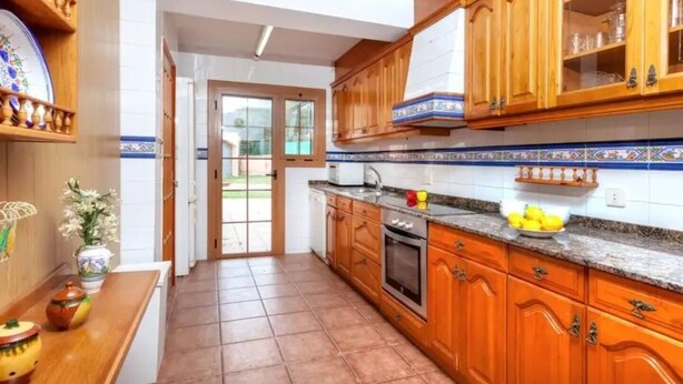 A kitchen with wooden cabinets, a countertop, and a tiled backsplash.