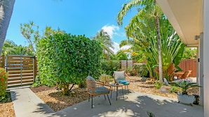 A patio with a seating area, a small table, and a variety of plants. - Ventur Escapade Heated Pool Guesthouse (Wilton Manors)