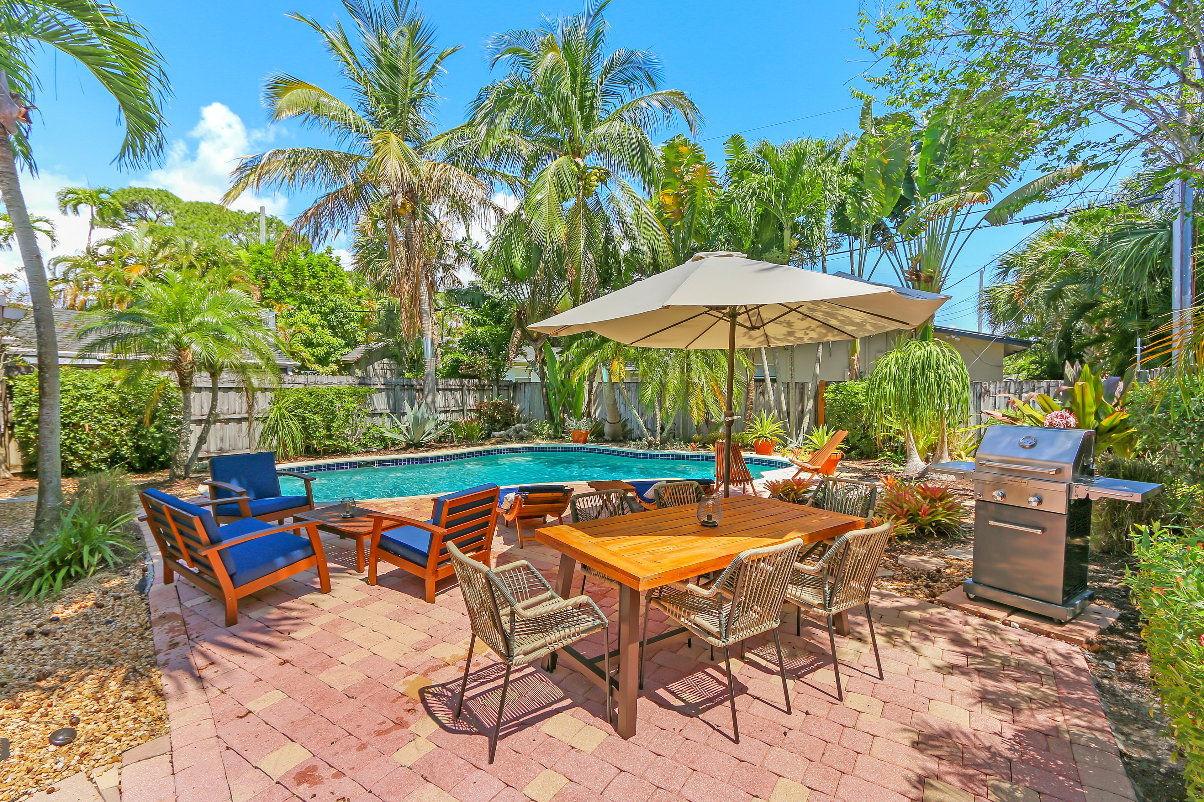 Um quintal com piscina, móveis de terraço e churrasqueira.