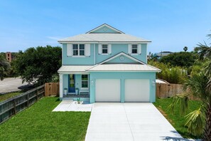 A two-story house with a garage, a front porch, and a well-maintained lawn. - Seashell Oasis - Heated Pool/Hot Tub/Putting Green/Walk to Beach (St. Augustine)