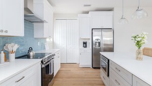 Eine moderne Küche mit weißen Schränken, einem Edelstahlkühlschrank und einer Kaffeemaschine.
