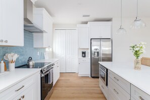 A modern kitchen with white cabinetry, a stainless steel refrigerator, and a coffee maker. - Seashell Oasis - Heated Pool/Hot Tub/Putting Green/Walk to Beach (St. Augustine)
