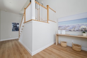 A staircase with wooden handrails and white balusters, leading to a landing with a welcome sign and a beach-themed artwork. - Seashell Oasis - Heated Pool/Hot Tub/Putting Green/Walk to Beach (St. Augustine)