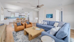 Ein modernes Wohnzimmer mit einem blauen Sofa, zwei Ledersesseln und einem Couchtisch aus Holz.