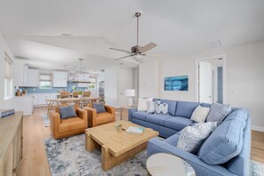 A modern living room with a blue sofa, two leather armchairs, and a wooden coffee table. - Seashell Oasis - Heated Pool/Hot Tub/Putting Green/Walk to Beach (St. Augustine)