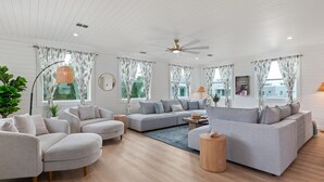 A spacious living room with a large grey sectional sofa, a smaller grey armchair, and a round wooden side table. - 3 houses/3 pools/2 rooftops/panoramic ocean & downtown views (St. Augustine)