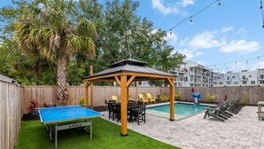 A backyard with a ping pong table, a covered seating area, a pool, and a wooden fence. - 3 houses/3 pools/2 rooftops/panoramic ocean & downtown views (St. Augustine)