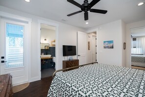 A bedroom with a bed, a ceiling fan, a television, and a bathroom visible through an open door. - 8 bedrooms, Sleeps 18, 2 Golf Carts, Heated Pool, Swim Spa, Hot Tub, Paddle Boards, Rooftop Deck (St. Augustine)