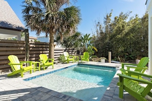 A swimming pool with a tiled edge, surrounded by green Adirondack chairs, and a wooden fence in the background. - 8 bedrooms, Sleeps 18, 2 Golf Carts, Heated Pool, Swim Spa, Hot Tub, Paddle Boards, Rooftop Deck (St. Augustine)