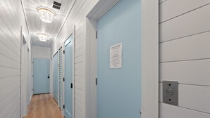 Un pasillo con puertas azul claro, paredes blancas y suelo de madera.