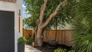 Una propiedad residencial con un árbol grande, un columpio, una cerca de madera y un camino de entrada pavimentado.