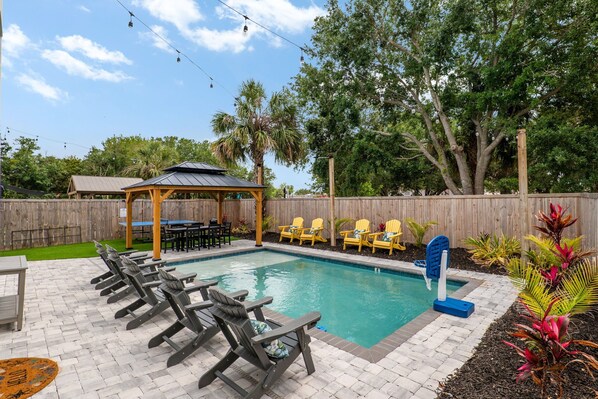 A backyard with a swimming pool, lounge chairs, a gazebo, and a wooden fence. - Osprey Nest - Rooftop/Pool/Water Views (St. Augustine)