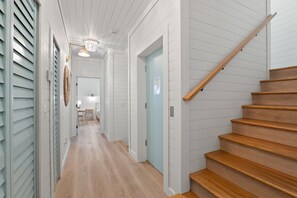 Ein Flur mit einer Holztreppe, weißen Wänden und einer Leuchte.