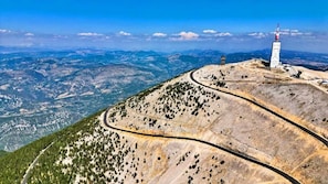 A mountainous landscape with a winding road, a tall monument, and a clear sky. - Chambres d'hôtes Arcadia les Suites (Crestet)