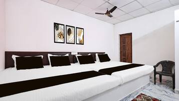 Una habitación de hotel con una cama grande, un ventilador de techo y una puerta.