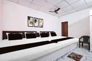 A hotel room with a large bed, a ceiling fan, and a door.