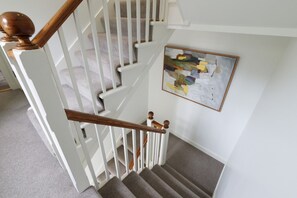 A staircase with white railings and wooden balusters, carpeted steps, and a painting on the wall. - Central Lerwick House, Modern, 2 Bathrooms, Garden (Lerwick)