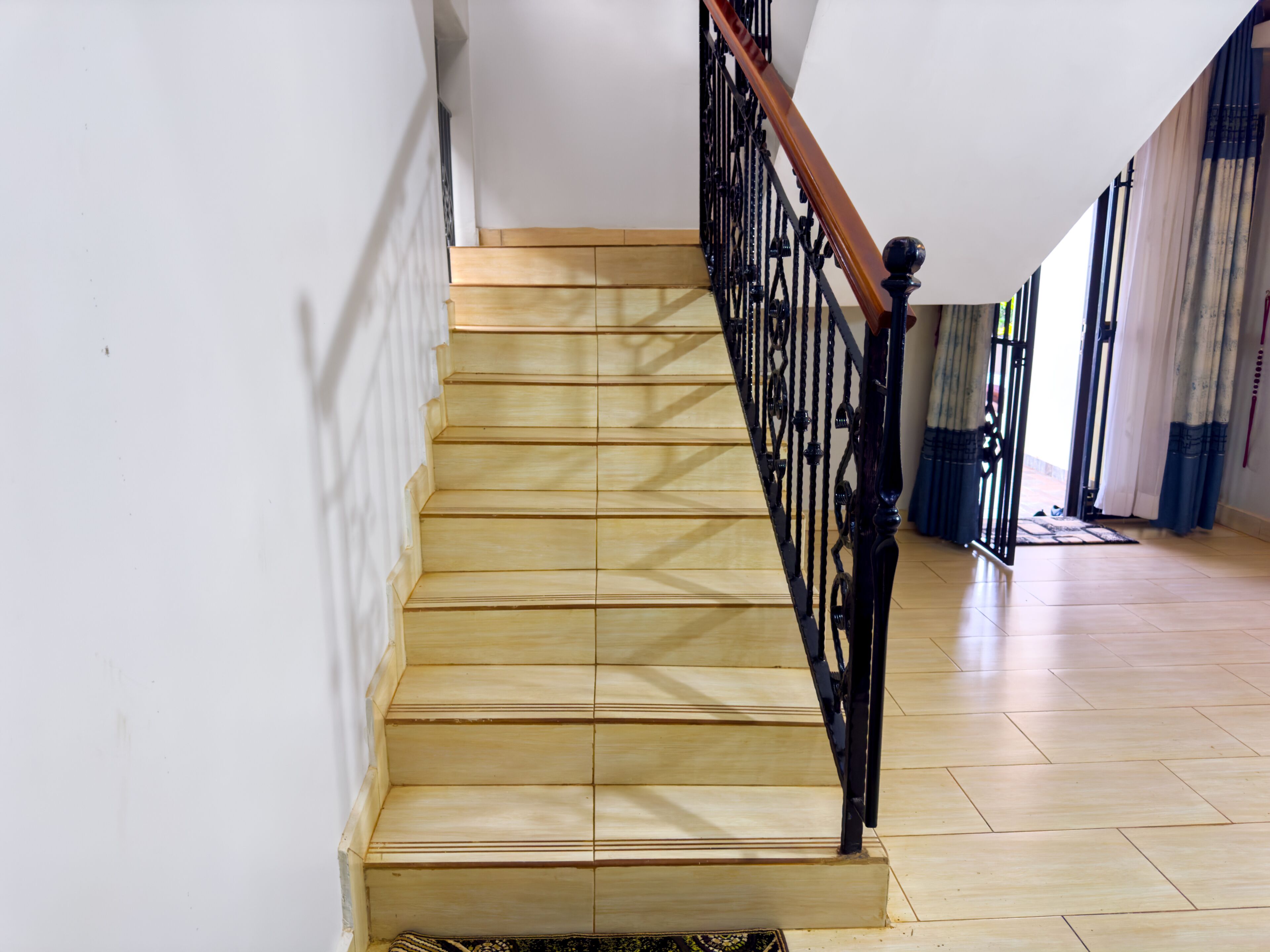 A wooden staircase with a black metal railing leading to a landing.