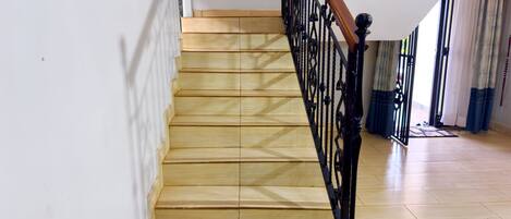 A wooden staircase with a black metal railing leading to a landing.