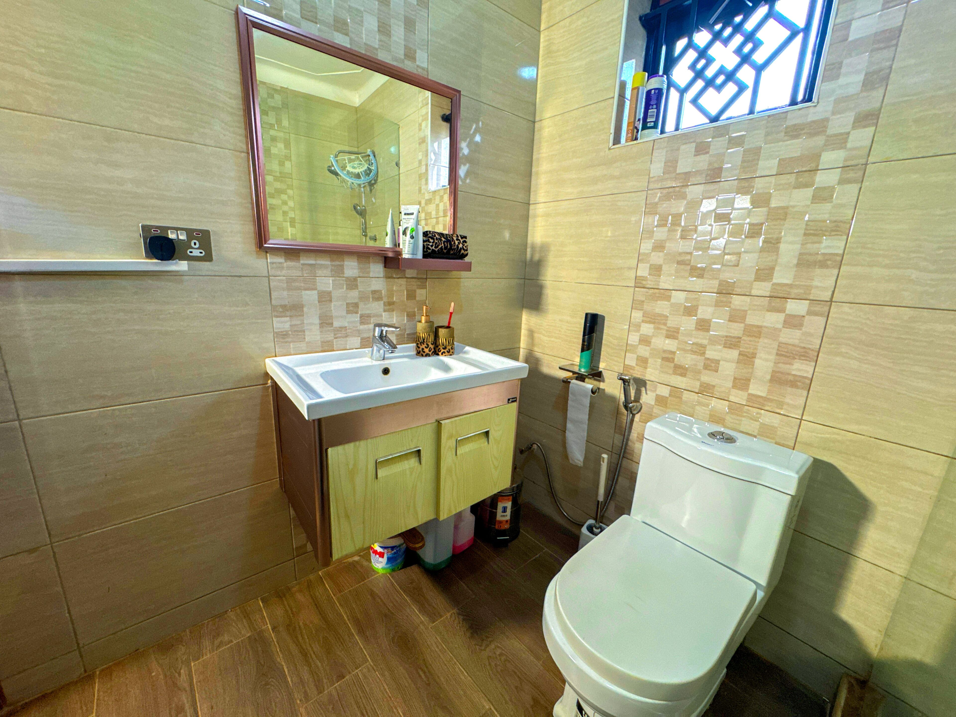 A bathroom with a white sink, a mirror, a toilet, and a shower area.
