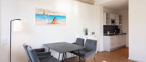 Une cuisine moderne avec des meubles blancs et un plan de travail noir.