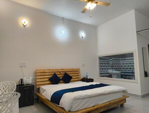 Un dormitorio con cama de madera, ventilador de techo y un ventanal con vistas al baño.