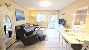 Ett modernt vardagsrum med en soffa, en pall, ett matbord och en tv.