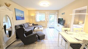 A modern living room with a sofa, ottoman, dining table, and a television. - Fantastic vacation rental "FeWo Lieblingsplatz" right on the beach in California O (Schönberg (Holstein))