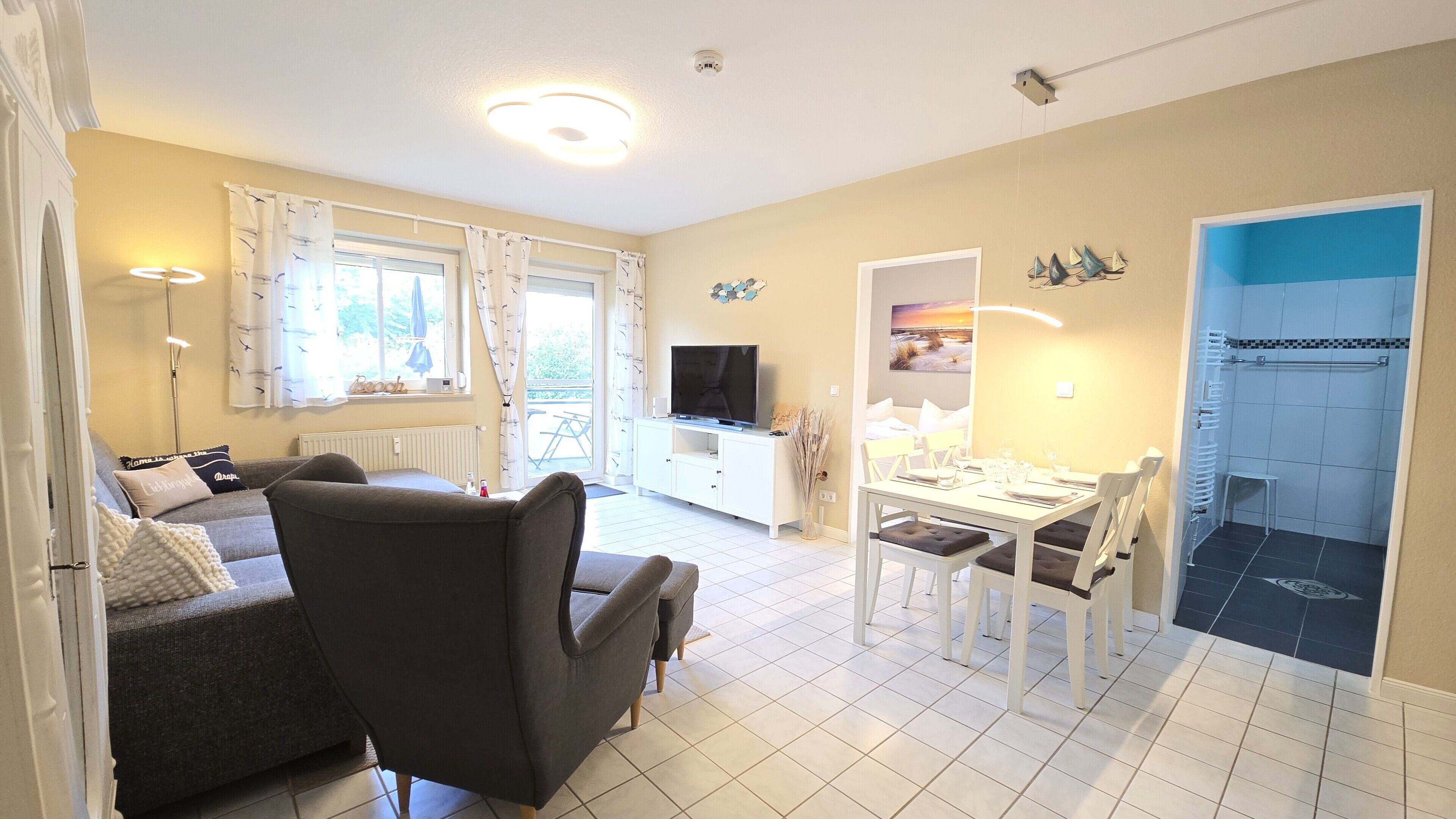 Un salon comprenant un canapé, un téléviseur, une table à manger et des chaises.