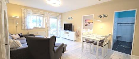 Una sala de estar con sofá, televisor, mesa de comedor y sillas.
