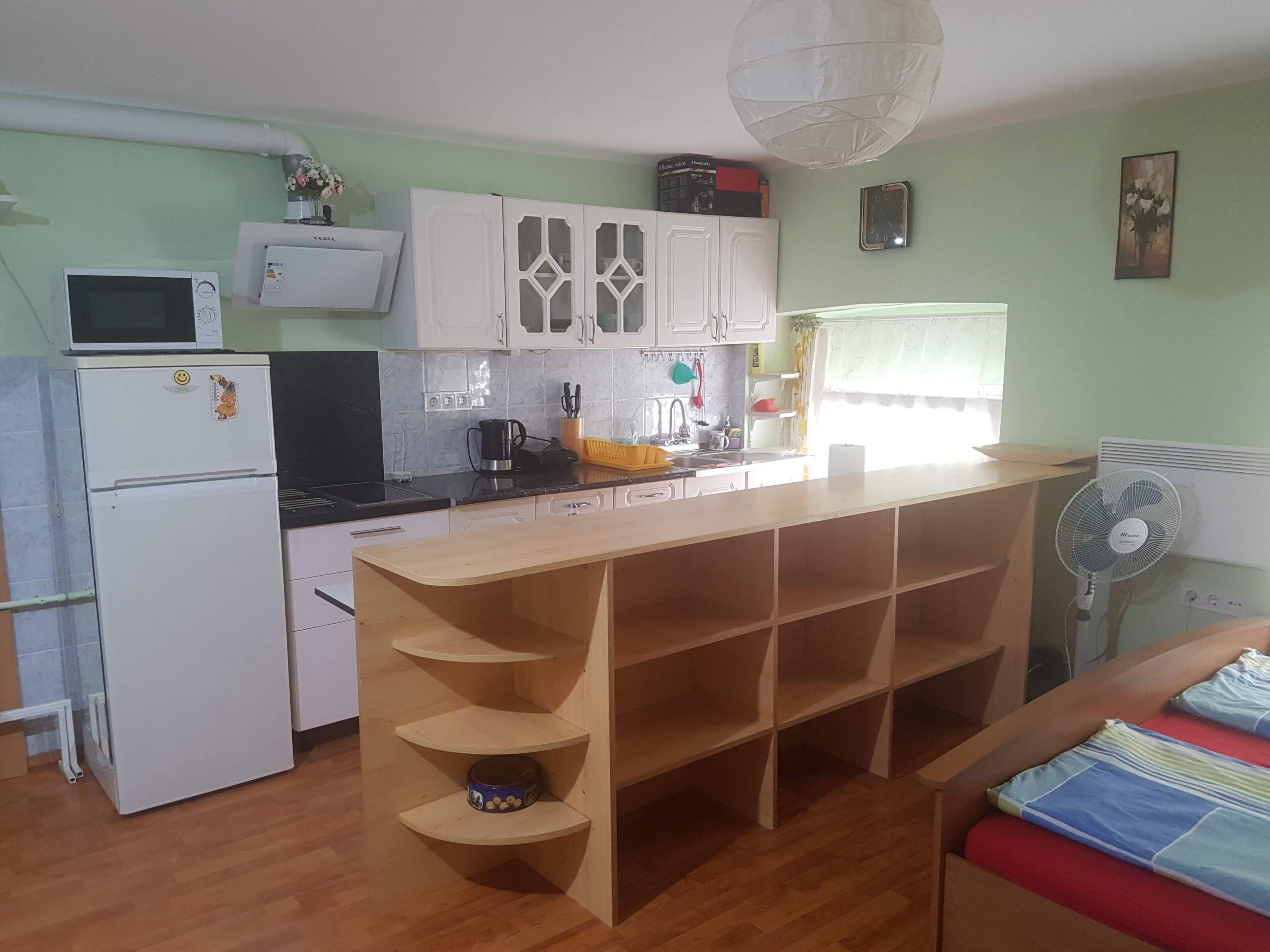 Eine kleine Küche mit Mikrowelle, Kühlschrank und einer Holz-Kochinsel mit Regalen.