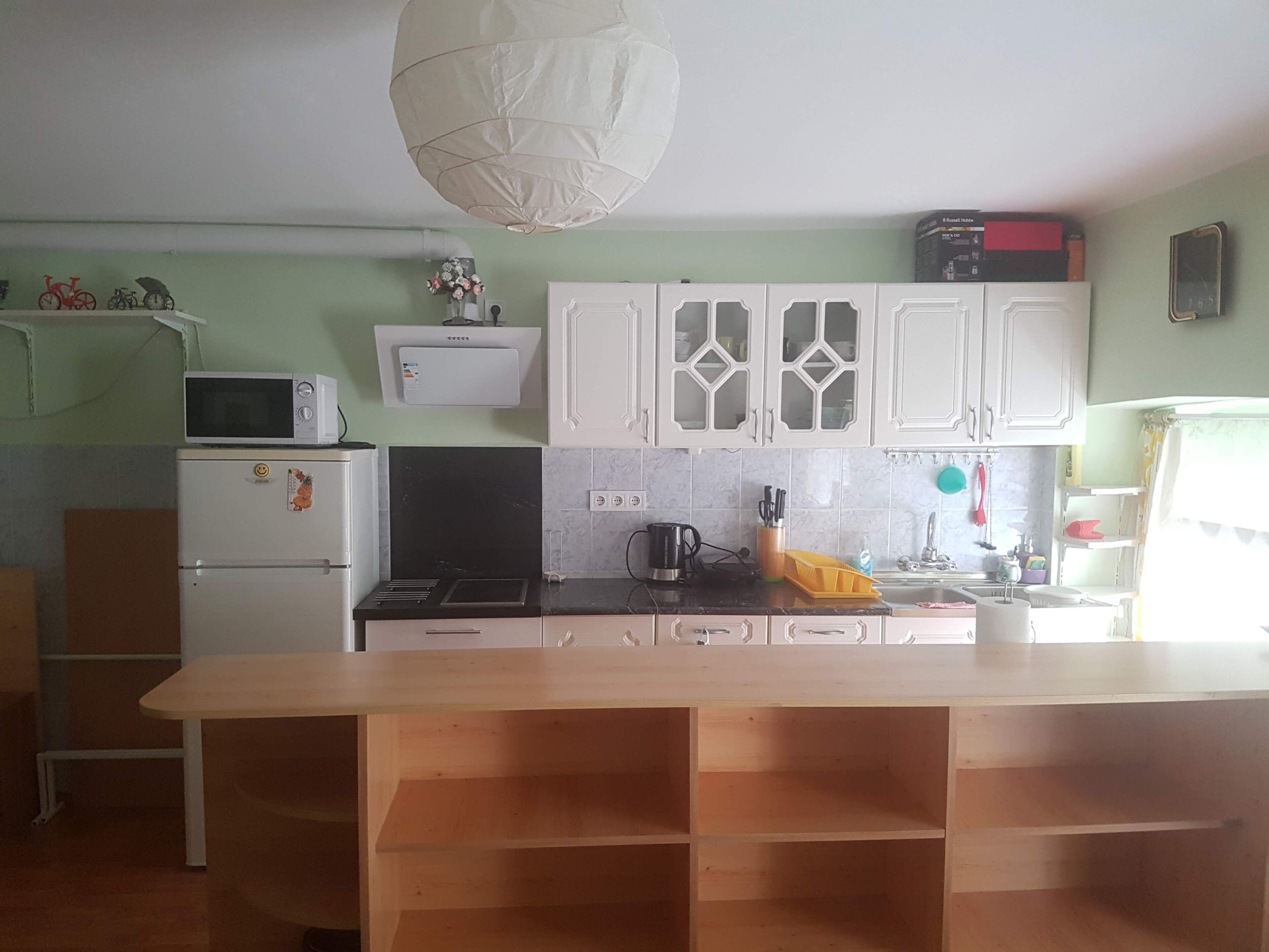 A kitchen with white cabinets, a microwave, a refrigerator, and a wooden table.