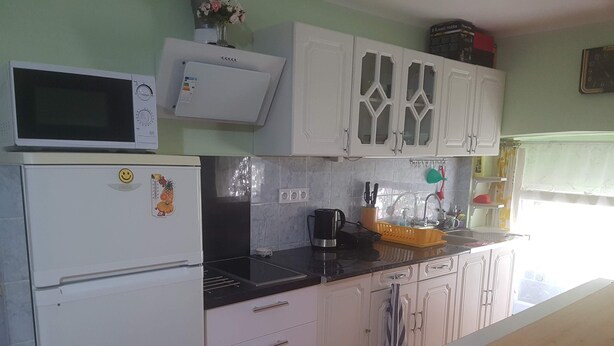 A kitchen with a microwave, refrigerator, and wooden countertop.