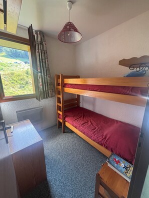 A bunk bed with a red mattress, a desk with a chair, a hanging lamp, and a window with curtains. - At the base of the slopes, a 3-bedroom apartment with a superb view in Plan Peisey (Peisey-Nancroix)