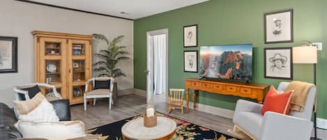 A living room with a green wall, a wooden cabinet, a television, and a lamp.